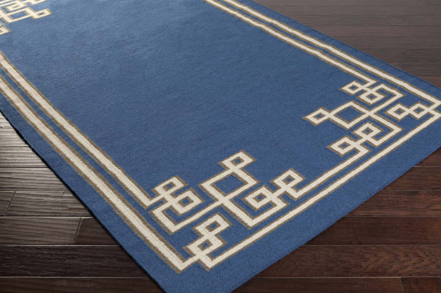 Close-up of the hand woven Hinckley Area Rug. Dark blue wool rug with light beige and gray geometric border. Corner