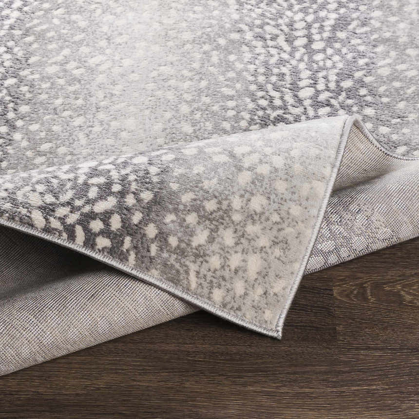 Close-up of Pointblank Black&Gray Antelope Print Rug showing its charcoal, ivory, and gray animal print design and machine-woven texture. Fold