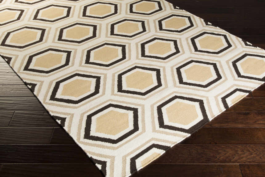 Close-up of Hydeville Area Rug. Hand-woven wool rug with a geometric hexagon pattern in black, camel, and light beige. Corner