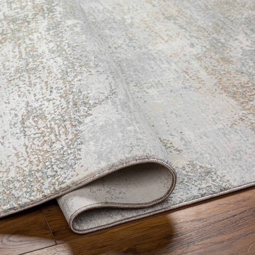 Close-up of the Ikram Thick Luxe Boutique Rug showing its gray, cloud gray, and beige abstract pattern and thick, soft texture. Fold