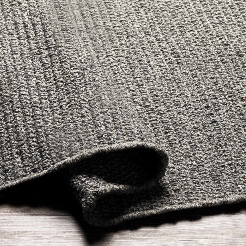 Close-up of the hand woven Innisfail Area Rug. Black and medium gray cotton and recycled PET yarn texture. Fold