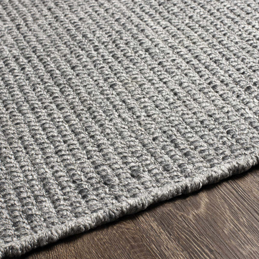 Close-up of the hand woven Innisfail Area Rug. Medium gray and black cotton rug with a textured, solid and striped design. Texture
