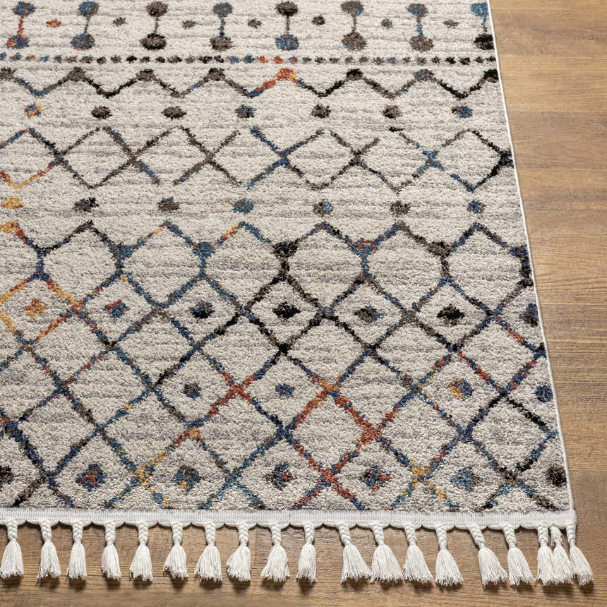 Close-up of Itogon Area Rug: geometric pattern in black, brick red, burnt orange, teal, and gray with white tassels. Front
