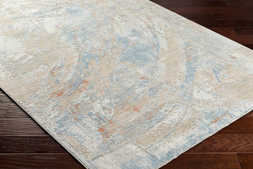 Close-up of Jaela Thick Luxe Area Rug showing its abstract design in gray, light brown, and hints of orange on dark brown wood floors. Corner