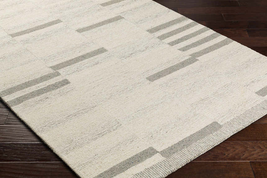 Close-up of the Jeri Modern Wool Rug, showcasing its beige and cloud gray geometric pattern and hand-tufted texture. Corner