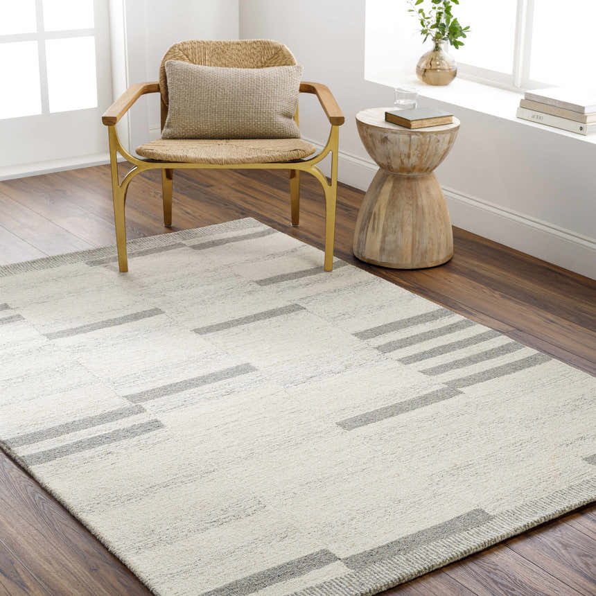 Modern living room scene with a beige Jeri Modern Wool Rug, woven chair, and wood side table. Roomscene-Rectangle
