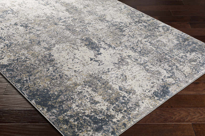 Close-up of the Kanahooka Area Rug, a contemporary rug in charcoal, beige, and blue, on a dark wood floor. Corner