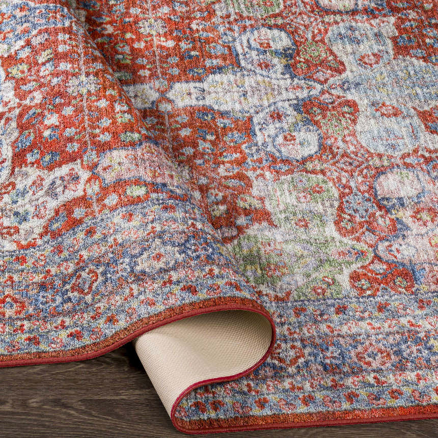 Close-up of the Kangundo Washable Area Rug showing its red, blue, and cream bohemian-style pattern and machine-woven texture. Fold