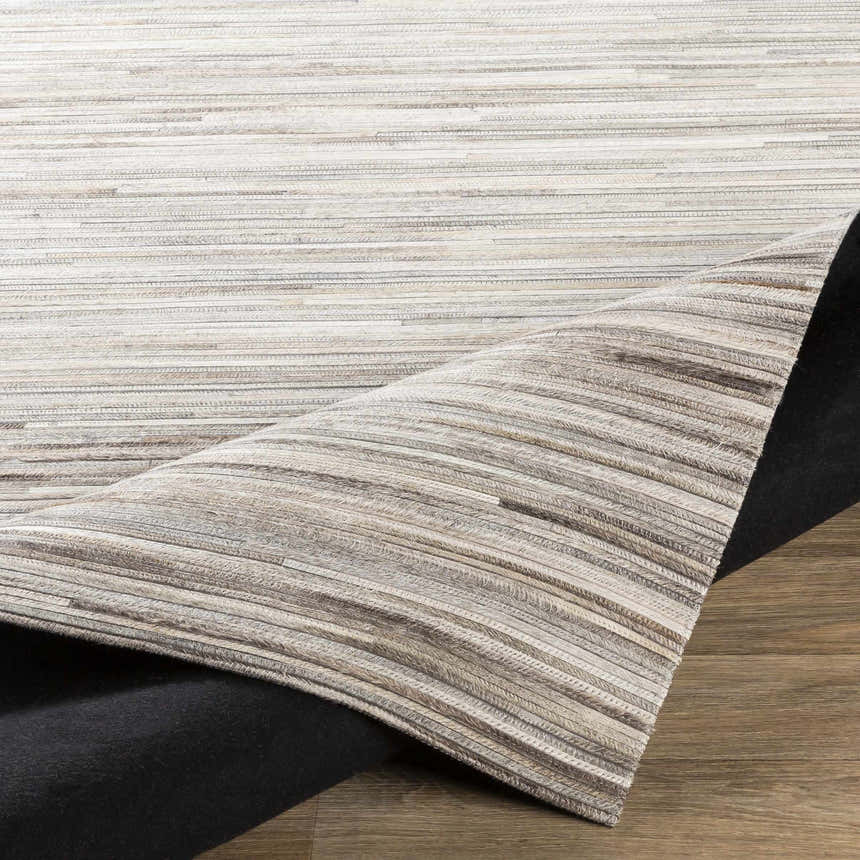 Close-up of the Karabar Premium Area Rug showing beige, brown, and gray hair on hide strips. Hand-crafted rectangular rug. Fold
