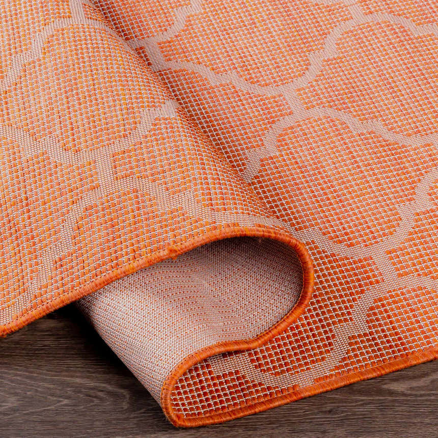 Close-up of the rust red Unique Outdoor Trellis Area Rug showing the trellis pattern and textured weave. Fold