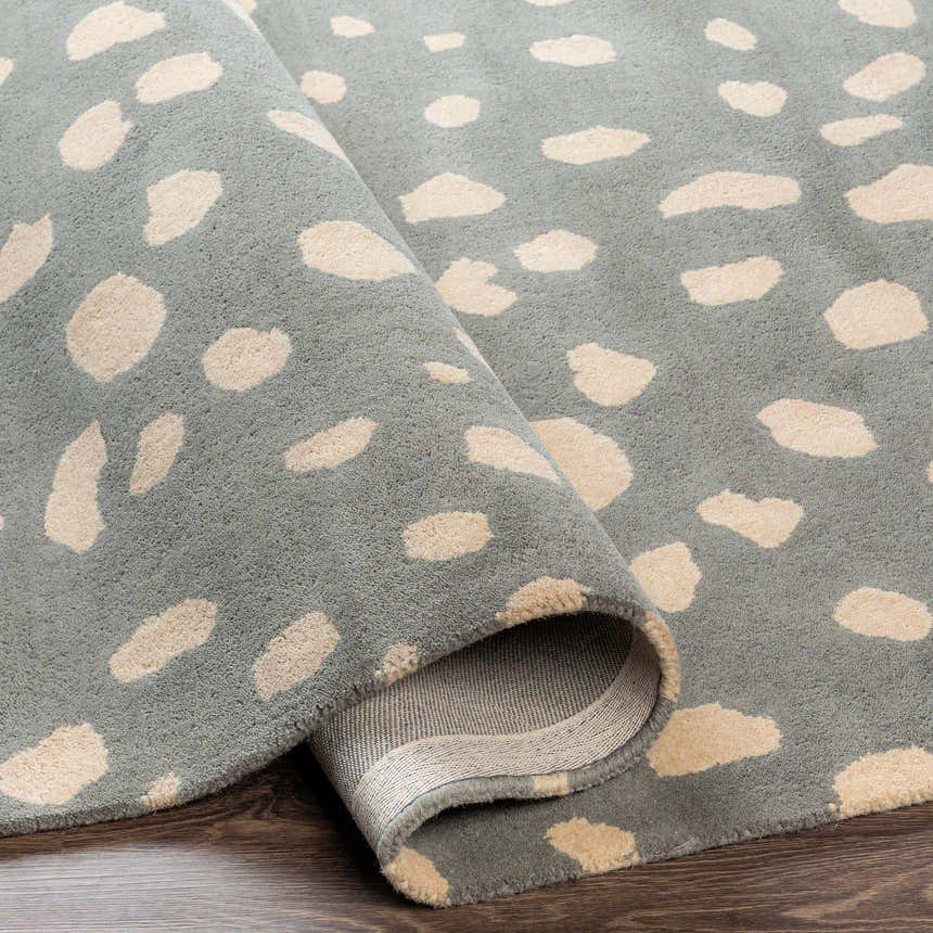 Close-up of the hand-tufted Kaweah Dalmatian Print Carpet. Features a gray background with ivory animal spots. Fold