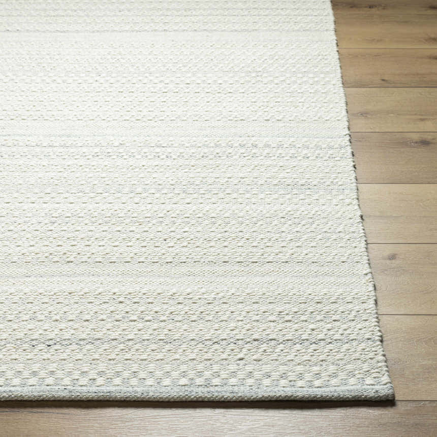 Close-up of the hand woven Kendi Light Slate Area Rug showing its cream and light slate colors and textured wool design. Front