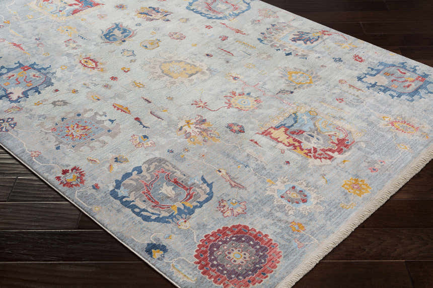 Close-up of the Kernersville Area Rug, a machine-woven rug with a light blue, burnt orange, and gray bohemian pattern. Corner