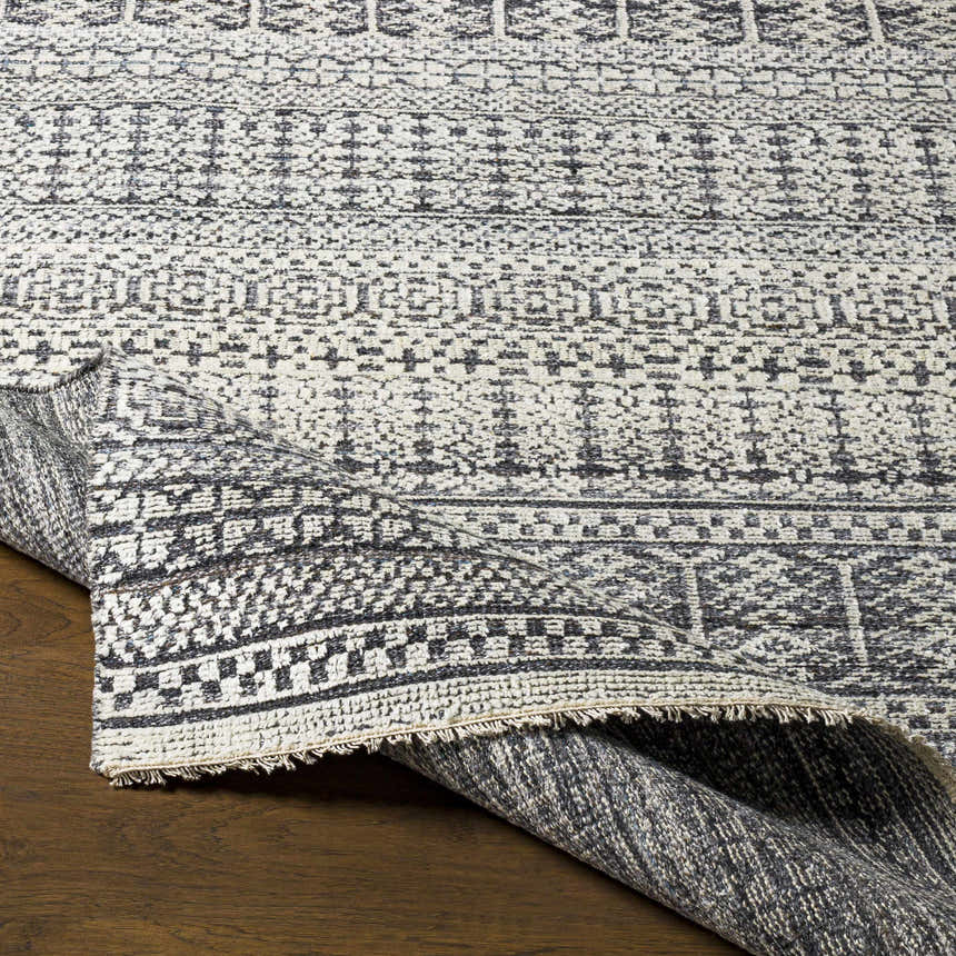 Close-up of the Kiara Area Rug showing its black, charcoal, and light gray Bohemian pattern and hand-knotted wool texture. Front