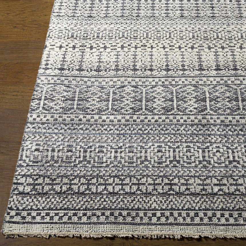Close-up of the Kiara Area Rug, a hand-knotted wool rug with a black and light gray geometric pattern on a wood floor. Front