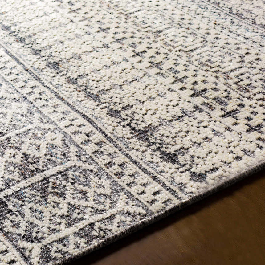 Close-up of the hand-knotted Kiara Area Rug. Oatmeal and charcoal wool rug with a traditional, geometric pattern. Fold