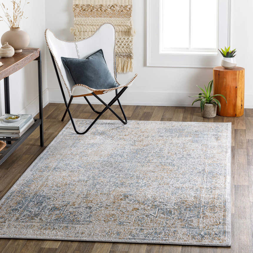 Living room scene with a Kintbury Area Rug in blue, brown, and off-white, styled with a white chair and wood accents. Roomscene-Rectangle