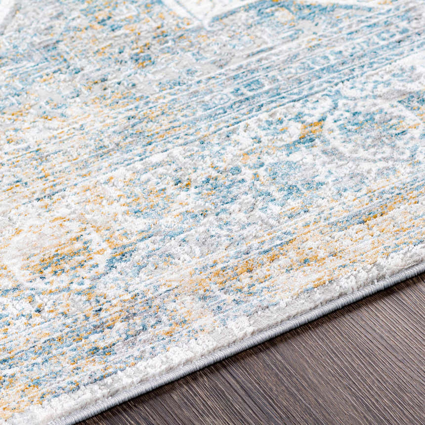 Close-up of the Kintbury Area Rug. Features a blue, mustard, and off-white bohemian pattern with a machine-woven texture. Texture