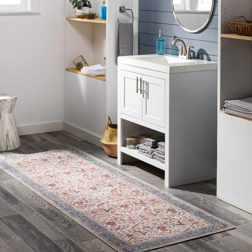 Bathroom scene with a Kislingbury Area Rug runner in beige, blue, and red, placed on dark wood floors. White vanity and shelving. Roomscene-Runner