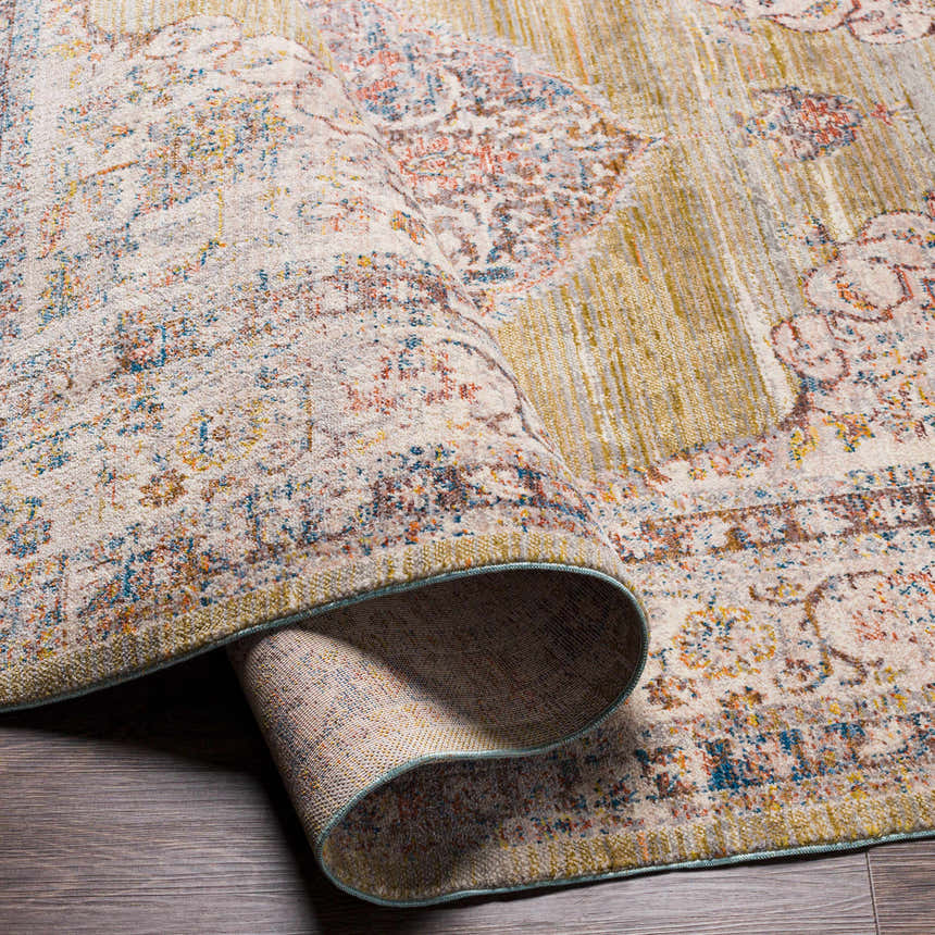 Close-up of the Klahanie Area Carpet showing its brick red, cream, blue, and mustard bohemian pattern and soft texture. Fold