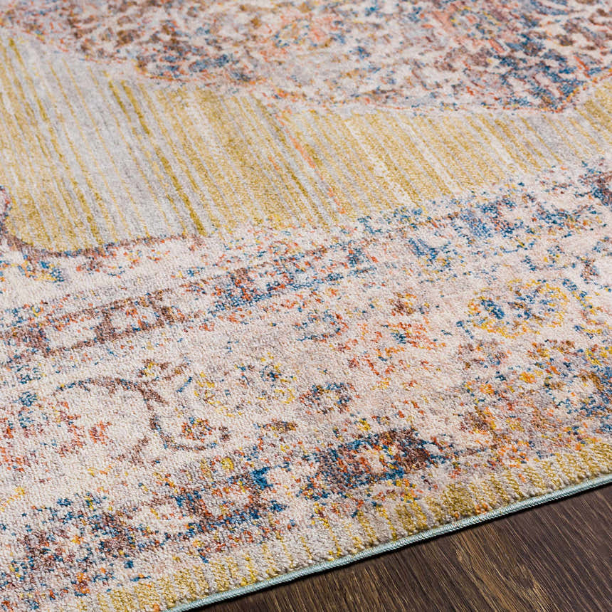 Close-up of Klahanie Area Carpet. Bohemian style rug in brick red, cream, blue, and mustard on a dark wood floor. Texture