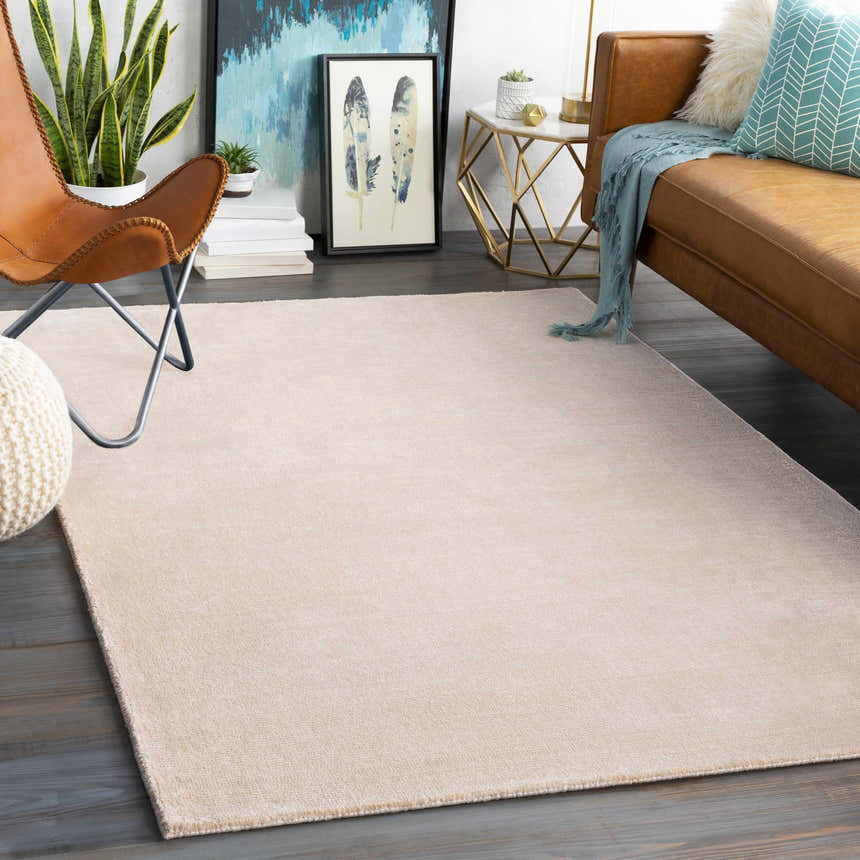 Living room scene with a peach Klickitat Area Rug, leather sofa, butterfly chair, and modern gold accent table. Roomscene-Rectangle
