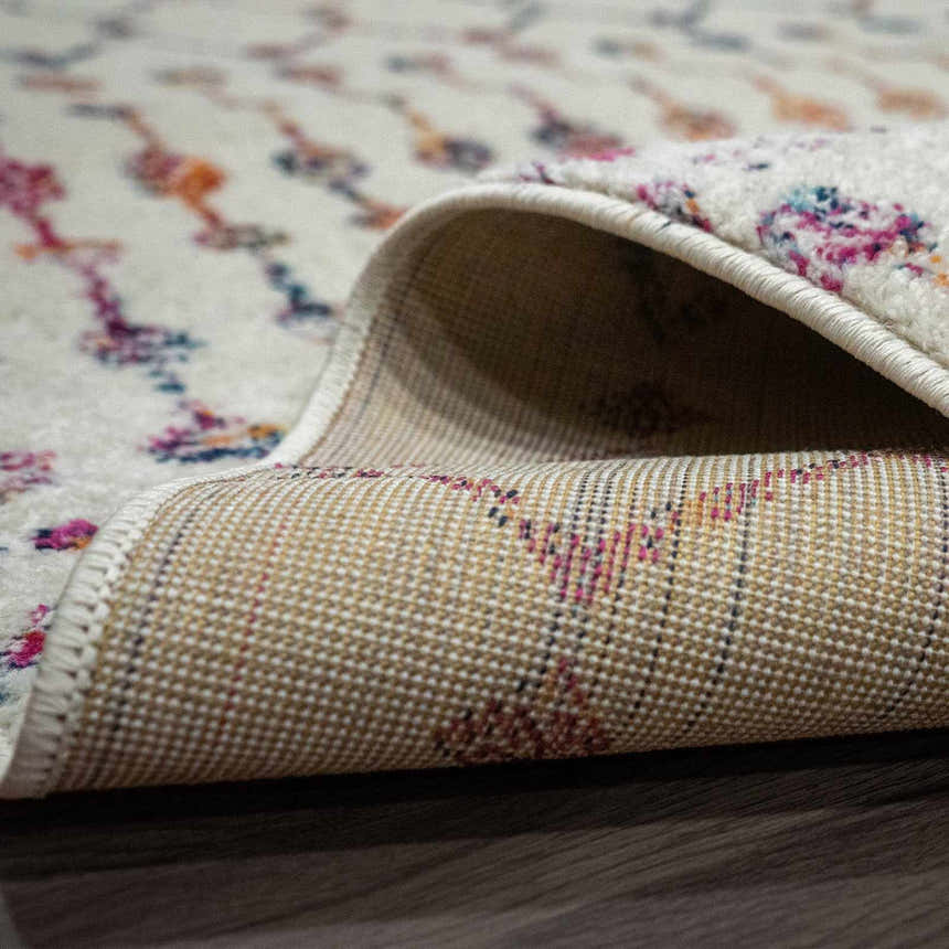 Close-up of the Marash KMRSH-4600 area rug showing its off-white base with colorful bohemian pattern and the rug's backing. Fold