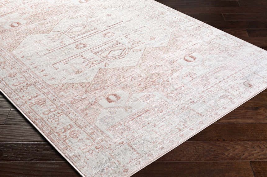 Close-up of the Kendal Area Rug showing a cream and pale pink traditional pattern on dark wood floors. Corner