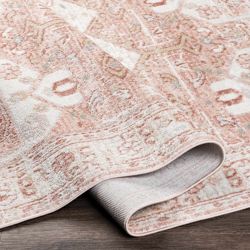 Close up of the Kendal Area Rug showing its light pink, cream, and beige traditional pattern and texture. Fold