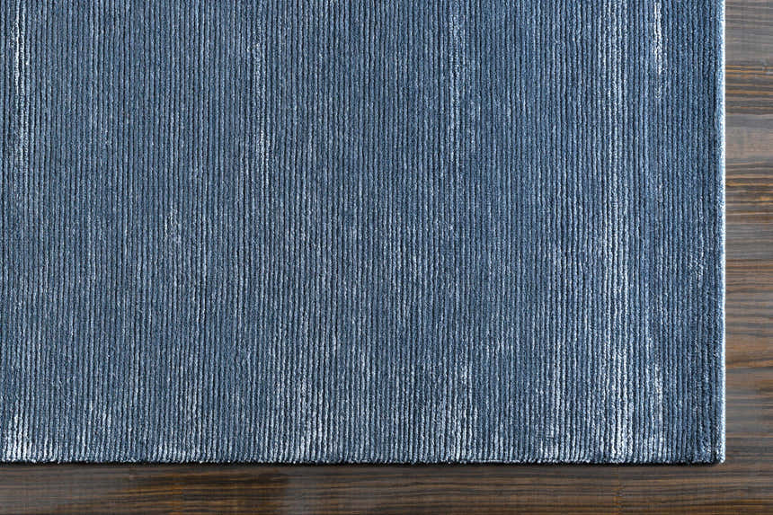 Close-up of the blue Kendall Carpet showing its hand-knotted texture and subtle vertical stripe design. Corner