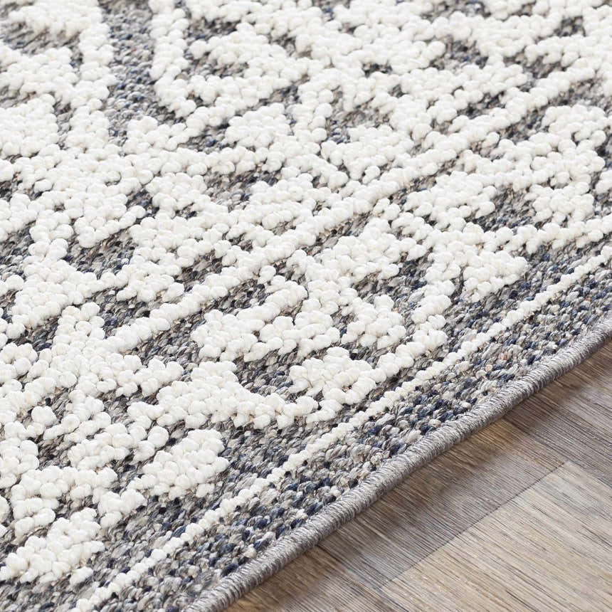 Close-up of the Kinglake Area Rug. White, raised pattern on a gray and black, machine-woven, polypropylene rug. Texture
