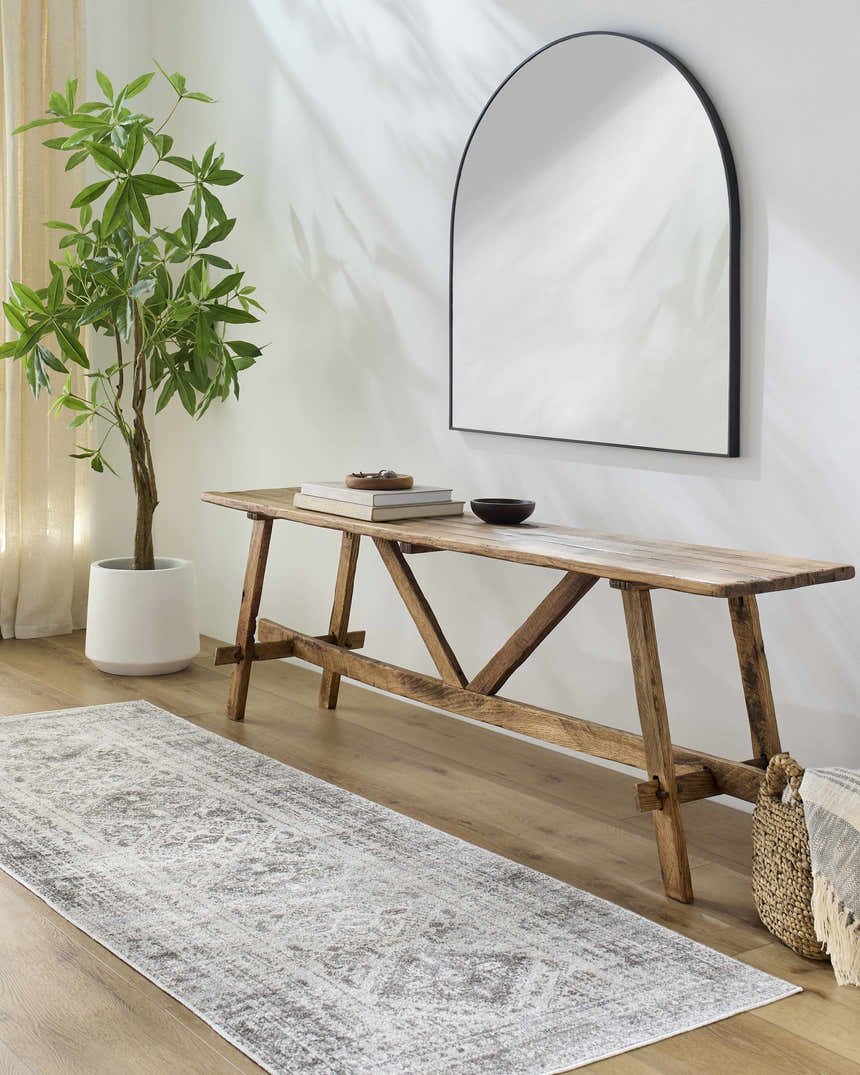 Entryway scene with Ladybrand Washable Area Rug in gray, wood bench, arched mirror, potted plant, and light wood floors. Roomscene-Runner