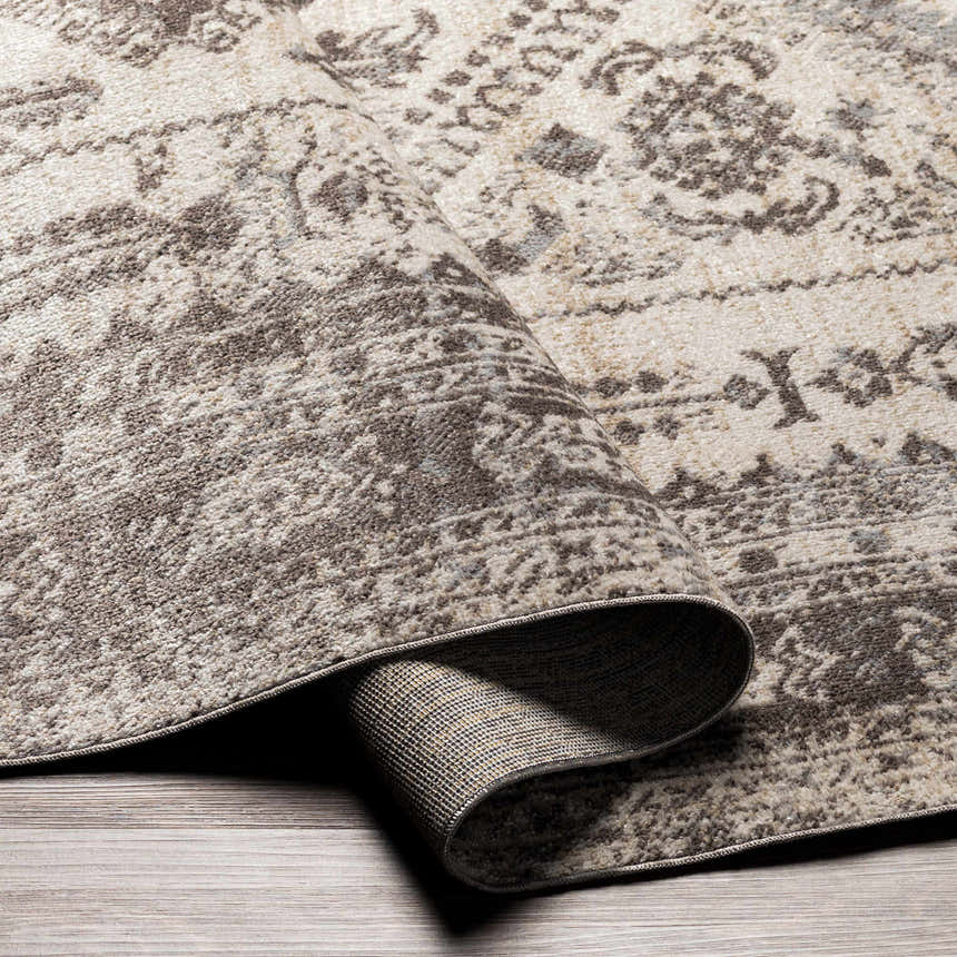 Close-up of the Ladybrand Washable Area Rug, showcasing its brown, beige, and gray traditional oriental pattern and machine-woven texture. Fold