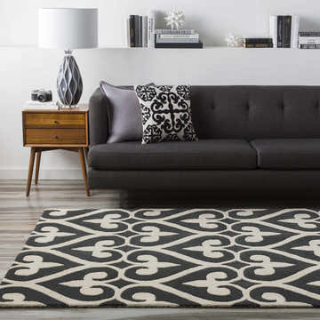 Living room scene with a black and cream Landa Area Rug, gray sofa, mid-century modern side table, and books on a shelf. Roomscene-Rectangle
