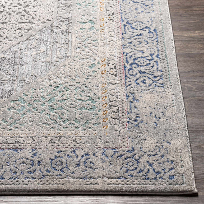 Close-up of the Laplace Area Rug showing its traditional blue, gray, and mustard vintage-inspired pattern and soft texture. Front