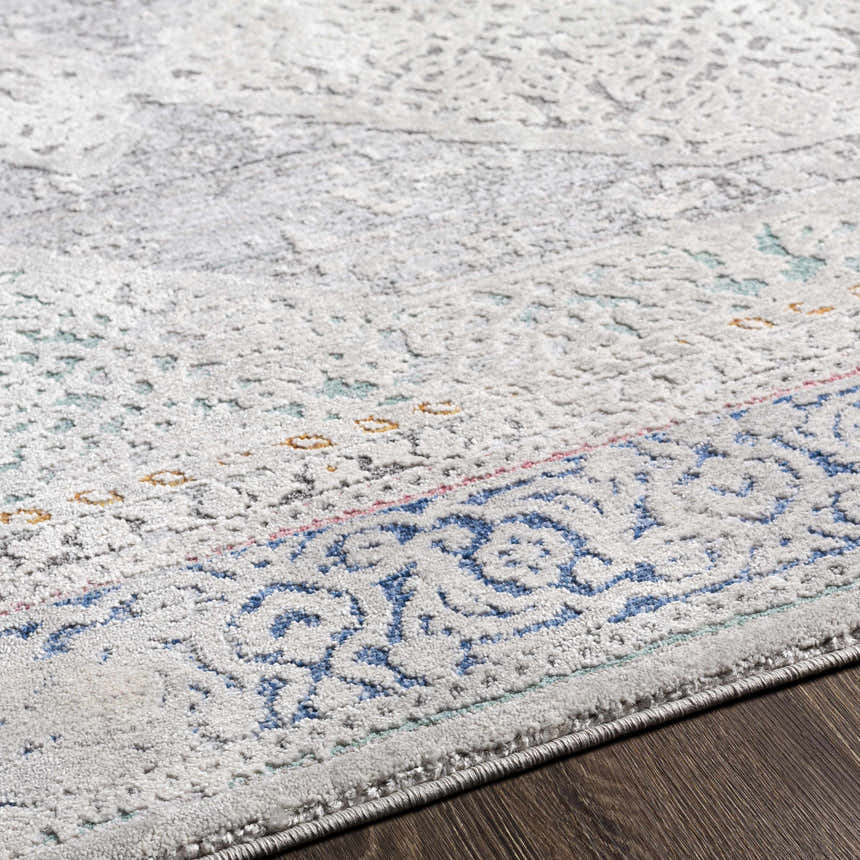 Close-up of the Laplace Area Rug, showing its vintage-style pattern in blue, gray, and hints of mustard. Soft texture. Texture