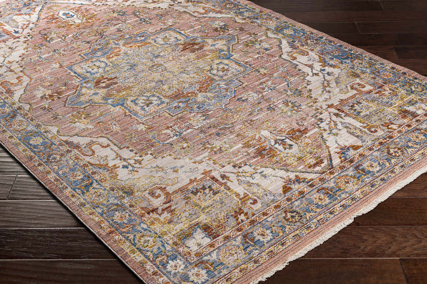 Close-up of the Lappe Area Rug. Bohemian style rug in cream, dark blue, peach, and rust colors on dark hardwood floor. Corner