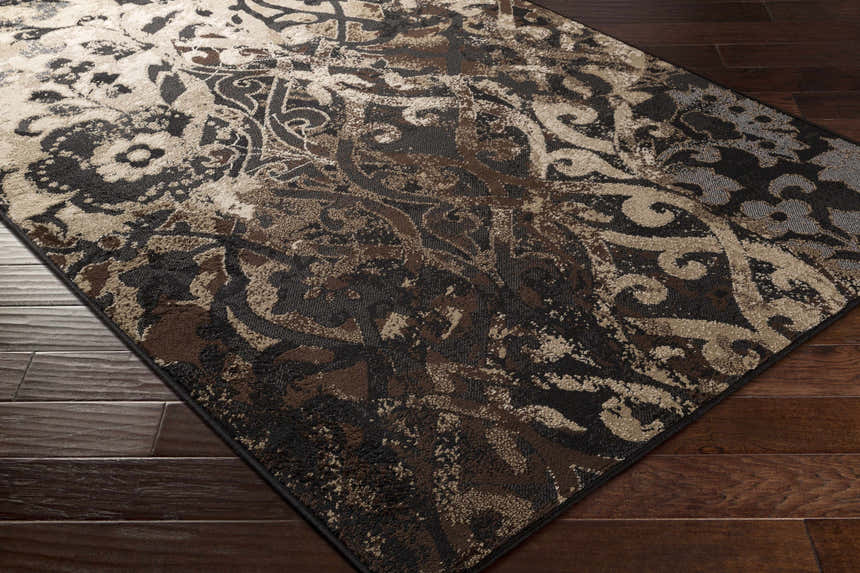 Close-up of the Lawtell Area Rug, a traditional design in black, brown, beige, and gray on a dark wood floor. Corner