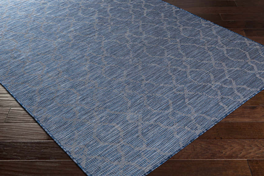 Close-up of the blue Lidlington Flatweave Area Carpet showing its geometric pattern and flat weave texture on a wood floor. Corner
