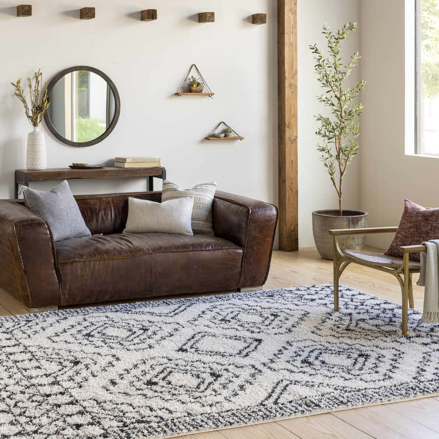 Living room scene with a brown leather sofa and black and cream Lloydminster Area Rug. Roomscene-Rectangle