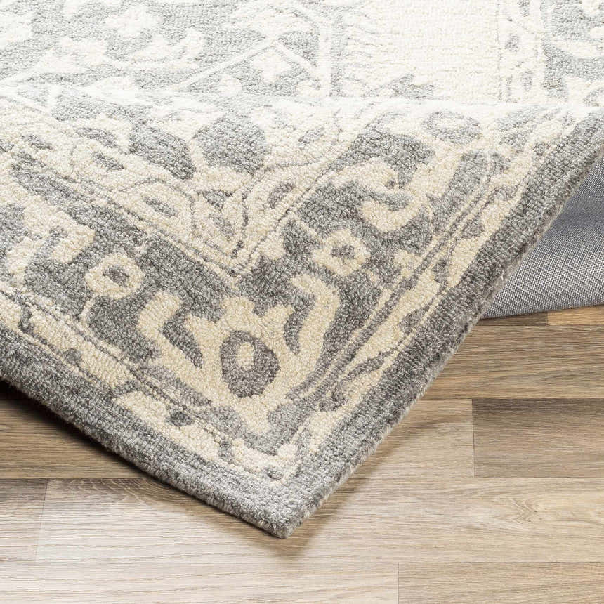 Close-up of the Longton Area Rug showing its charcoal and gray traditional pattern and hand-tufted wool texture. Fold