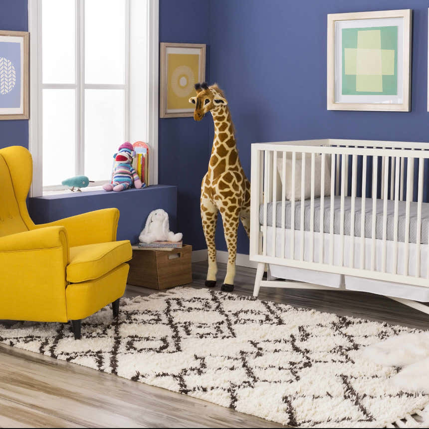 Nursery with white crib, yellow chair, and ivory Lothian Area Rug with charcoal geometric pattern. Roomscene-Rectangle