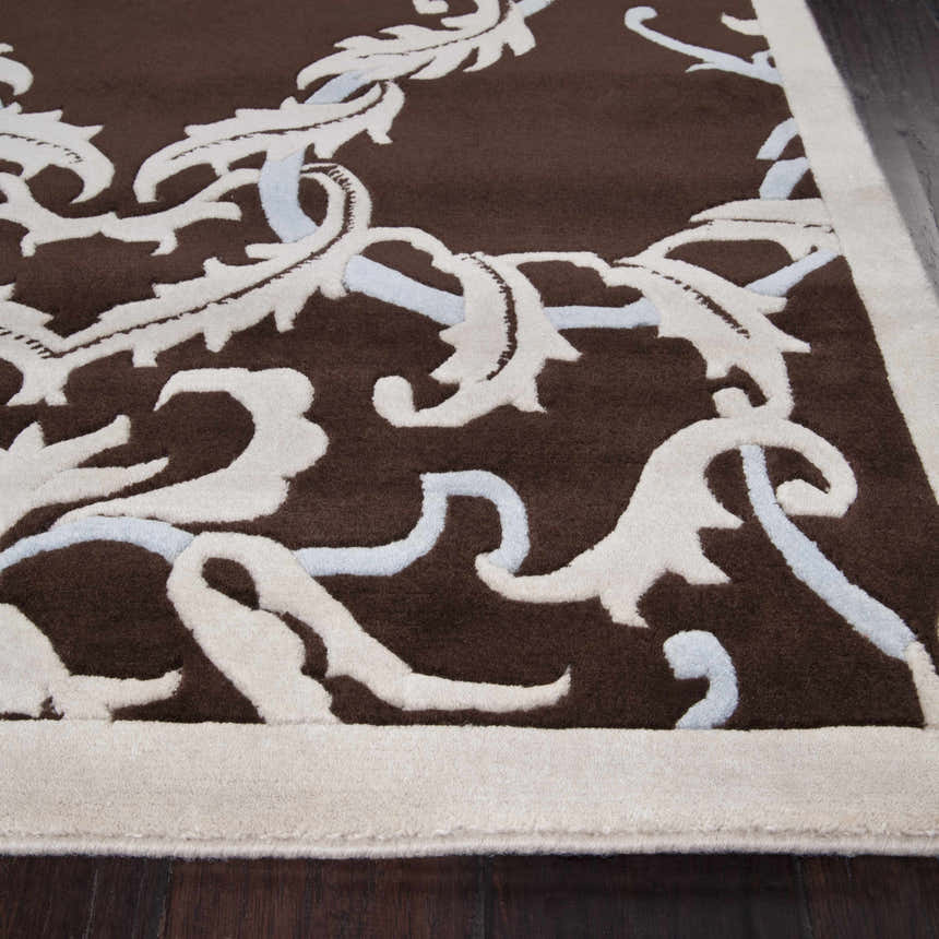 Close-up of the Ludlam Area Carpet showing a brown wool rug with a white and silver blue floral pattern. Texture