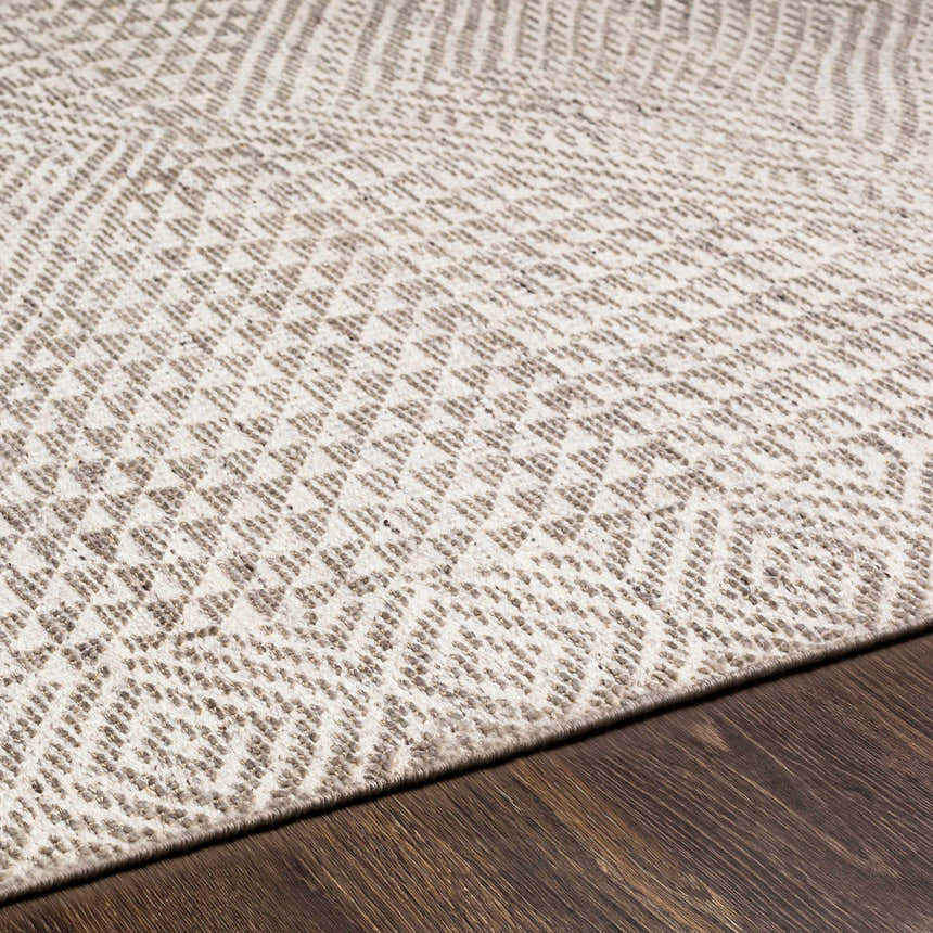 Close-up of the Lusacan Area Carpet. Hand-knotted rug with a geometric pattern in charcoal, gray, and off-white. Viscose material. Texture