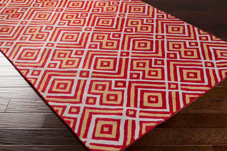 Close-up of the Loyalhanna Area Rug featuring a geometric pattern in gray, medium brown, and rust on dark wood flooring. Corner