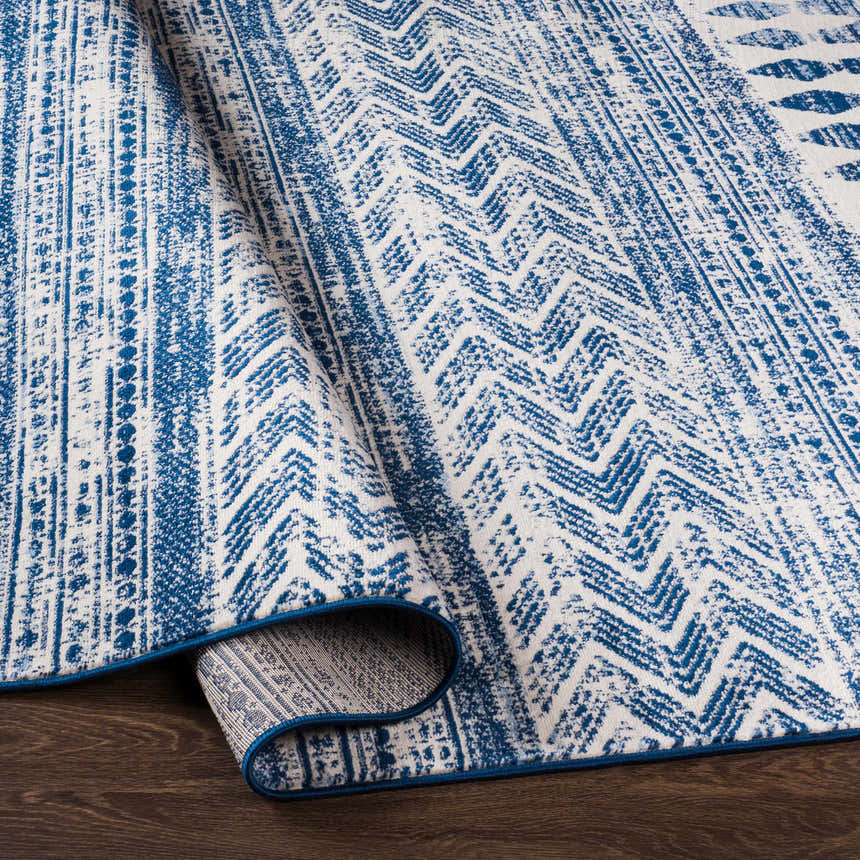 Close-up of the Mahinog Area Carpet, featuring a blue and off-white bohemian-inspired geometric pattern. Fold