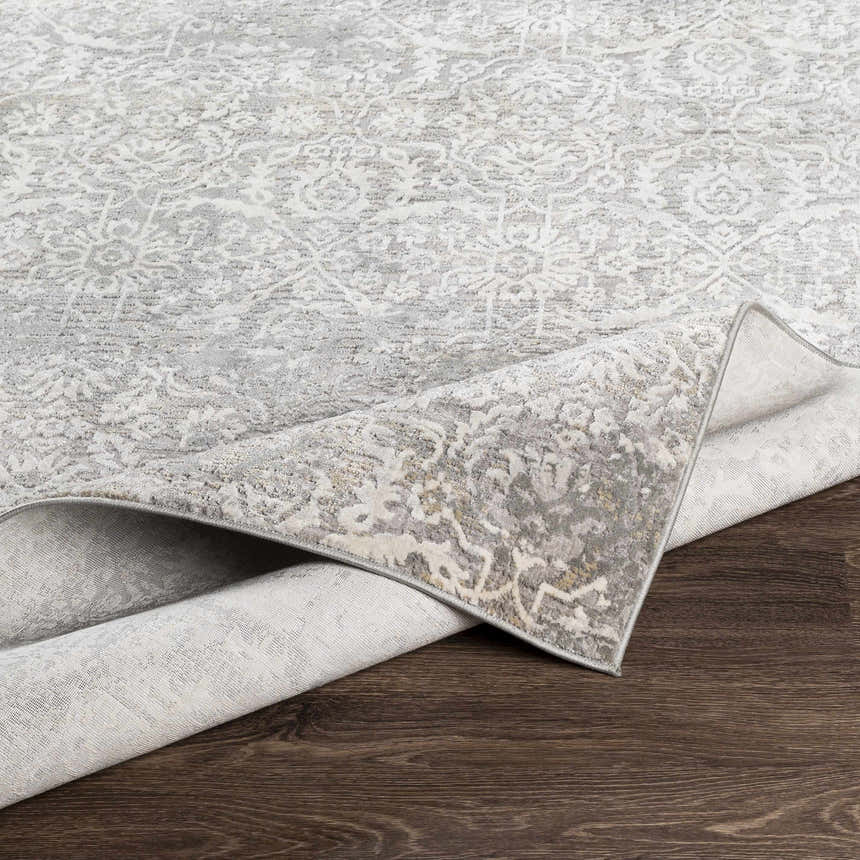 Close-up of the Mandurah Area Rug, showing its charcoal, cream, and gray traditional pattern and machine-woven texture. Fold