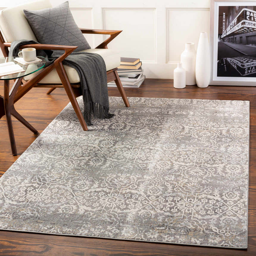Living room scene with a charcoal and cream Mandurah Area Rug, white chair, and dark wood floors. Roomscene-Rectangle