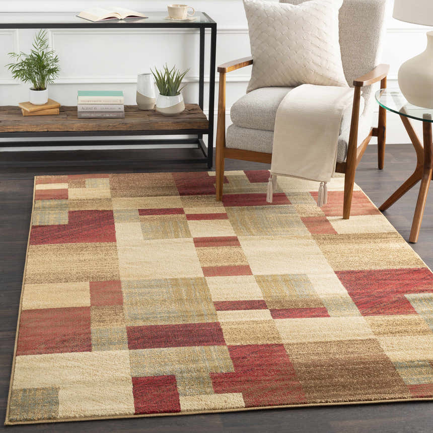 Living room scene with a Maumee Brown Mosaic Performance Rug, chair, and side tables. The rug features a geometric pattern in brown and red. Roomscene-Rectangle