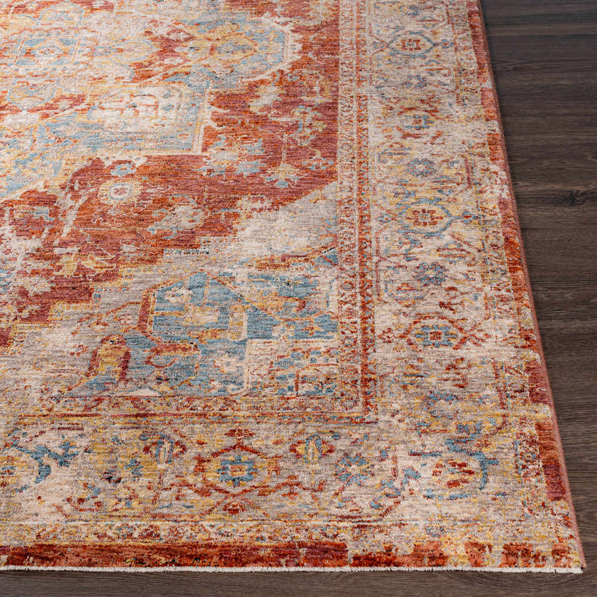 Close-up of the Powassan Area Rug showing its brick red, teal, and beige traditional design on dark wood floors. Front